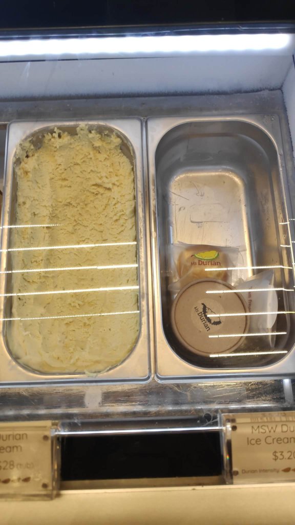 Image Description: Two stainless oblong food container on the left - yellow-white ice cream and right side - ice cream cup and bun inside the plastic packaging