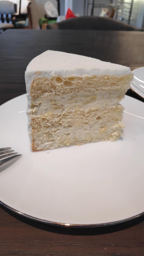 Image description:Durian cake glazed with white icing on the top placed in white round plate
